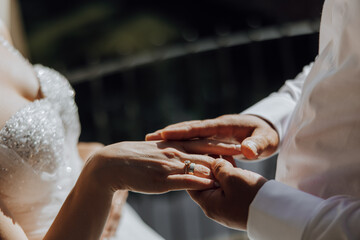 A bride and groom are getting married and are about to exchange rings. The bride is wearing a white dress and the groom is wearing a white shirt