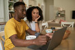 Young multiethnic couple using a laptop during breakfast in the morning