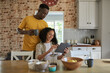 Smiling multiethnic couple using a tablet in their kitchen in the morning