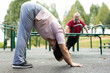 Mature woman doing yoga outdoors in city sports ground