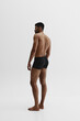 © master1305 - Young African-American man with relief strong back, muscular body standing shirtless in black boxers isolated on white background. Concept of male beauty, sport, body care, health, fitness