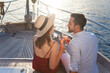 Couple in love drinking wine on yacht by sea. Travel on sailboat at sunset. Happy travelers relaxing and enjoying summer vacation. Intimate romantic dating, celebration. Beautiful man and woman