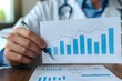 © Anastasiia - A male doctor presenting a graph on health insurance business growth. Concept Healthcare, Insurance, Business, Growth, Presentation