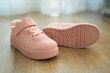 Child's pink sneakers on wooden floor. Cute girl's shoes on floor