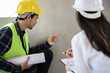 Female civil engineer with inspection check sheet consult with construction site foreman technician for inspect building condition defect pointing wall crack wait for repair.