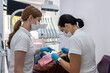 female patient being examined and treated by female dentist and an assistant in dental clinic.