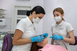 female patient being examined and treated by female dentist and an assistant in dental clinic.