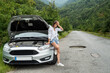caucasian woman stand near broken car with mountain background