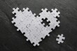 Heart made of puzzles with missing piece on black table