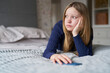 Unhappy Teenage Girl With Mobile Phone At Home Anxious About Social Media And Online Bullying