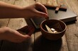 Donate and give concept. Woman putting coin into bowl with money at wooden table, closeup