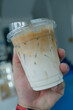 Cool iced latte coffee, the bottom as milk top by coffee shot in a plastic glass on hand