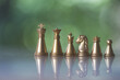 Sets of golden chess pieces on nature background. The photo of gold chess, king, rook, bishop, queen, knight, and pawn.