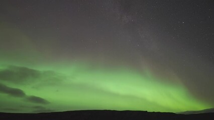 Wall Mural - A time-lapse video capturing the stunning Aurora Borealis illuminating the tranquil waters of a fjord on a dark winter night.