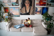 Happy couple hugging, dreaming, resting on sofa after a working day in spacious bright loft room of gallery. In interior of art studio composition of many paintings on wall. Slow life concept. 