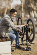 Man Fixes Bicycle Chain on Bench