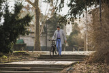 Fototapeta  - Man Walking With Bicycle Down Stone Steps in Urban Park