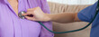 Closeup hands nurse or caregiver sitting on sofa holding stethoscope listen heartbeat with senior woman in living room at home, doctor check cardiologist disease with elderly, medical and insurance.