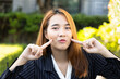 Friendly happy Asian office worker woman, making cute Asian pose, pointing at her cheek in smart casual corporate suit