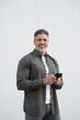 © Stock 4 You - Vertical portrait hispanic business man using smartphone mobile phone for online financial bank transactions. 40s freelancer entrepreneur holding cellphone isolated on white background, looking camera