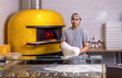 Chef preparing pizza dough. The process of making pizza. Skilled chef preparing dough for pizza rolling with hands while working in a pizza place. The process of making pizzas