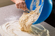 Hand woman pours dough from a bowl onto the table. Pouring sourdough discard from a bowl directly on the table. Healthy baking with sourdough starter. Woman kneading dough by hand yeast dough