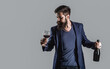 Red wine in a glass. Sommelier man, degustator, winery. Man holding bottle with champagne. Man in suit toasting with sparkling glass of red wine. Red wine in bottle, wine glass