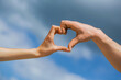 Girl and man hands in heart form over blue sky background. Love, friendship concept. Girl and male hand in heart form love blue sky. Female and man hands in form of heart against the sky
