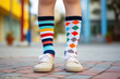 Little boy wearing different pair of socks and white sneakers outdoors. Kid foots in mismatched socks. Odd Socks day, Anti-Bullying Week, Down syndrome awareness concept