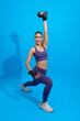 Workout. young asian woman doing squat exercise with dumbbell isolated on blue studio fitness gym Background.