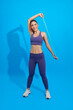 Asian strong sporty girl using resistance band in her exercise routine isolated on blue background. Strength and motivation