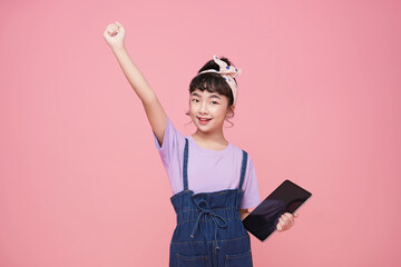 Canvas Print - smiling young Asian girl holding tablet computer with hand up happy isolated on pink background.