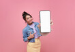 Beautiful Asian woman showing and pointing finger to smartphone mockup of blank screen isolated on pink background.