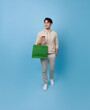 Full length young asian shopper man walking and holding shopping bag feeling happy excited for discount promotion isolated on blue background.