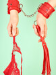 Woman's hands holding red whip for adult role play games and red panty over mint background