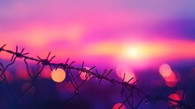Barbed Wire Fence With Purple Light, Bokeh Effect, Purple And Red Lights In The Background.