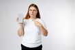 Sad 30s girl showing blank screen mobile phone on white background, studio portrait.