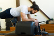 Man practicing on pilates reformer bed in studio