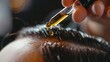 A close-up of oil droplets used for restoring and nourishing hair, applied to the scalp in a hairdresser spa salon setting.