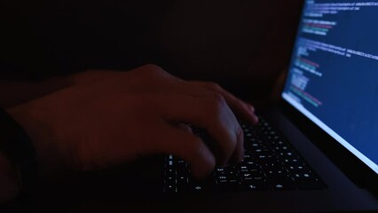 Wall Mural - A young man programmer coding on a laptop in the dark with a view of the lights of the night city, color lighting in the room. Coding and hacking concept. Saint Petersburg, Russia - 20 April 2024