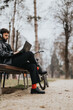 © qunica.com - Stylish male entrepreneur in casual black attire conducts remote work on a laptop while sitting on a bench in an urban park, with his bicycle nearby.