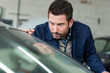 © auremar - mechanic inspecting car windshield in auto repair shop