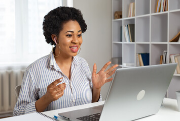 A young African woman talks while looking at the laptop screen at a remote video conference or webinar. Online training.