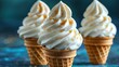   Three ice cream cones with whipped cream and cinnamon sprinkles on top of each cone, arranged on a blue background