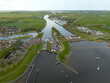 Aerial drone view of lock complex in Frisian city of Stavoren. Large pumping station beside bridge and sluice and historic town with canal, lake, and waterways