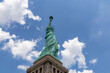 A close up on an iconic representation of freedom and independence, the Statue of Liberty with flaming torch on Liberty Island. The Lady on a Pedestal is surrounded by clouds. American history.