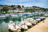 Fototapeta  - A serene view of the Porto Cristo harbor in Mallorca, showcasing moored boats and the surrounding landscape