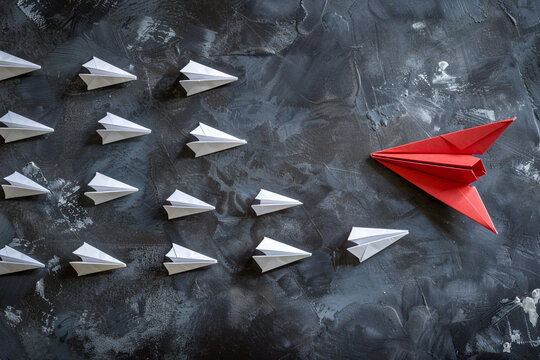 A single red paper plane leading white ones, embodying leadership, direction, and the courage to be different 