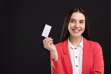 Happy woman holding blank business card on black background. Space for text