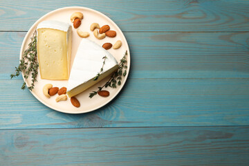 Wall Mural - Tasty Camembert cheese with thyme and nuts on light blue wooden table, top view. Space for text